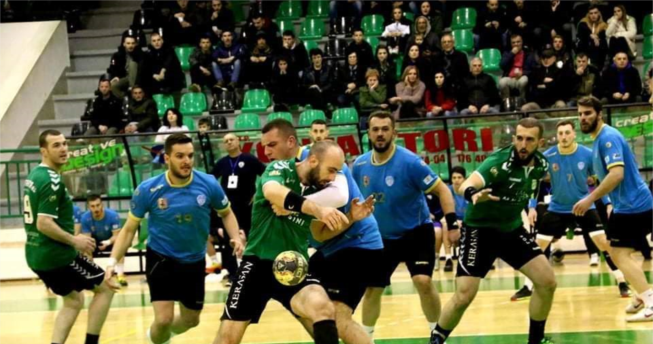 Lojtarit i ka rënë topi nga dora për shkak se kundërshtari i tij e ka kapur për fanellë me qëllim që t’a ndalojë lëvizjen e tij, kurse mbrapa tyre janë lojtarët e të dy ekipeve.