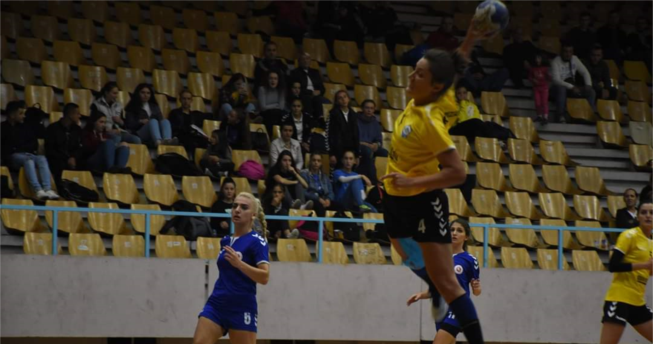 Në foto shihet një lojtare me top në dorë e cila është hedhur lartë për të shënuar në portë, mbrapa saj është një bashkëlojtare dhe dy lojtare të ekipit kundërshtar.