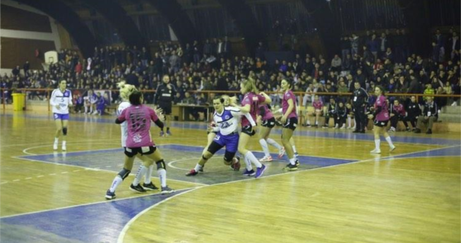 Një lojtare është duke vrapuar dhe është kapur nga dy kundërshtare me qëllim që t’a ndalojnë, dy kundërshtare tjera i ka mbrapa kurse përballë ka një bashkëlojtare e cila gjithashtu është kapur nga një kundërshtare.